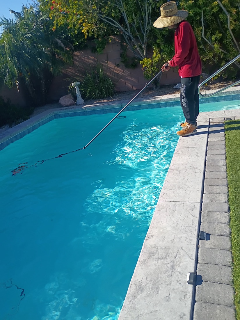 Excellent Pool Care technician brushing pool walls